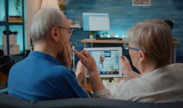 aged man and woman talking to dentist on online video call